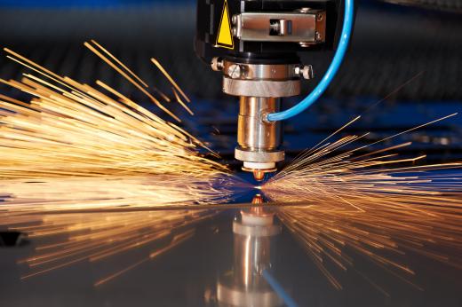 A carbon dioxide laser cutter is used to cut a sheet of metal.